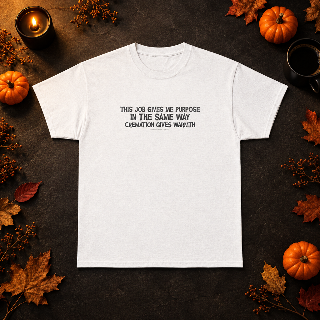 Never Been Deader "Cremation" white tee laid flat on dark slate with pumpkins, autumn leaves, a candle and coffee.