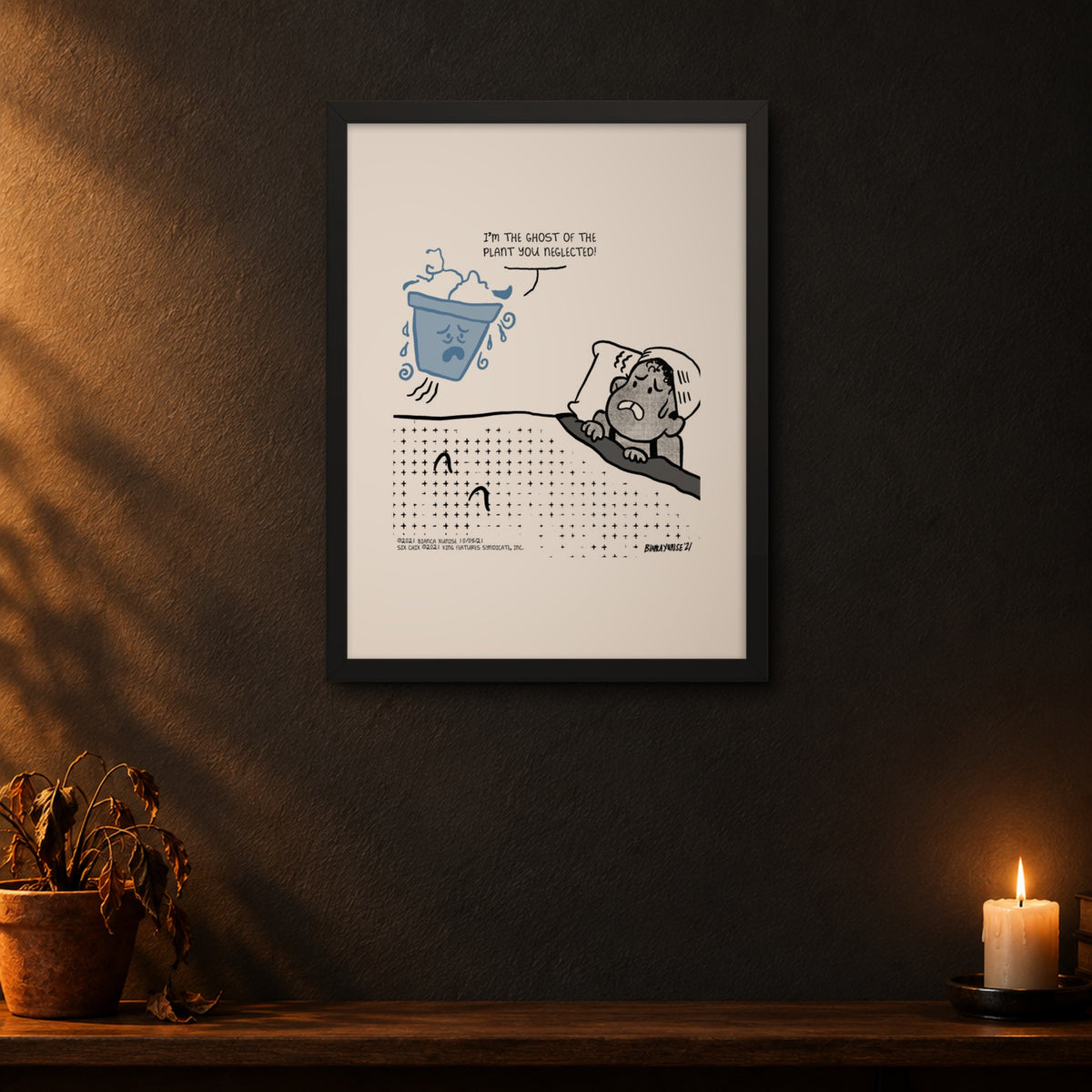 Six Chix Ghost Plant framed print by Bianca Xunise on a dark wall above a wilted houseplant and candle.
